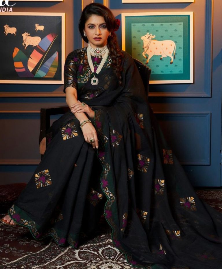Premium AI Image | A woman wearing a black saree with a large gold necklace  and earrings